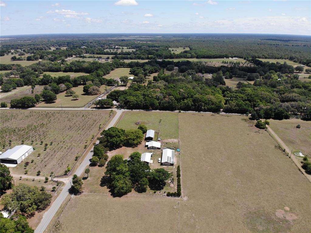 An aerial view shows a rural property with several buildings surrounded by large pastures and trees — 3650 NE 95TH STREET, ANTHONY, FL
