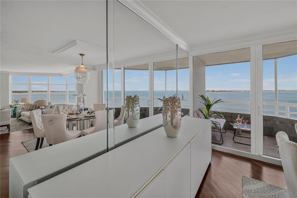 A dining area with a mirrored wall and balcony overlooking the ocean — 888 BLVD OF THE ARTS UNIT 1008, SARASOTA, FL