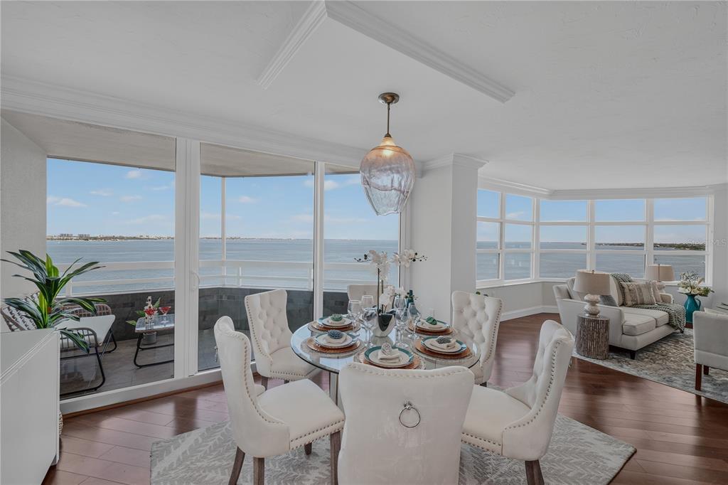 A dining area with a glass table and water views through floor-to-ceiling windows — 888 BLVD OF THE ARTS UNIT 1008, SARASOTA, FL