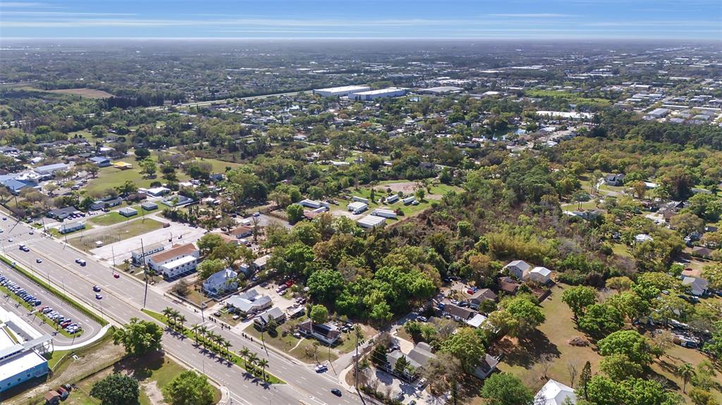An aerial view shows a suburban area with a main road, residential houses, and trees — 2008 53RD AVENUE E, BRADENTON, FL
