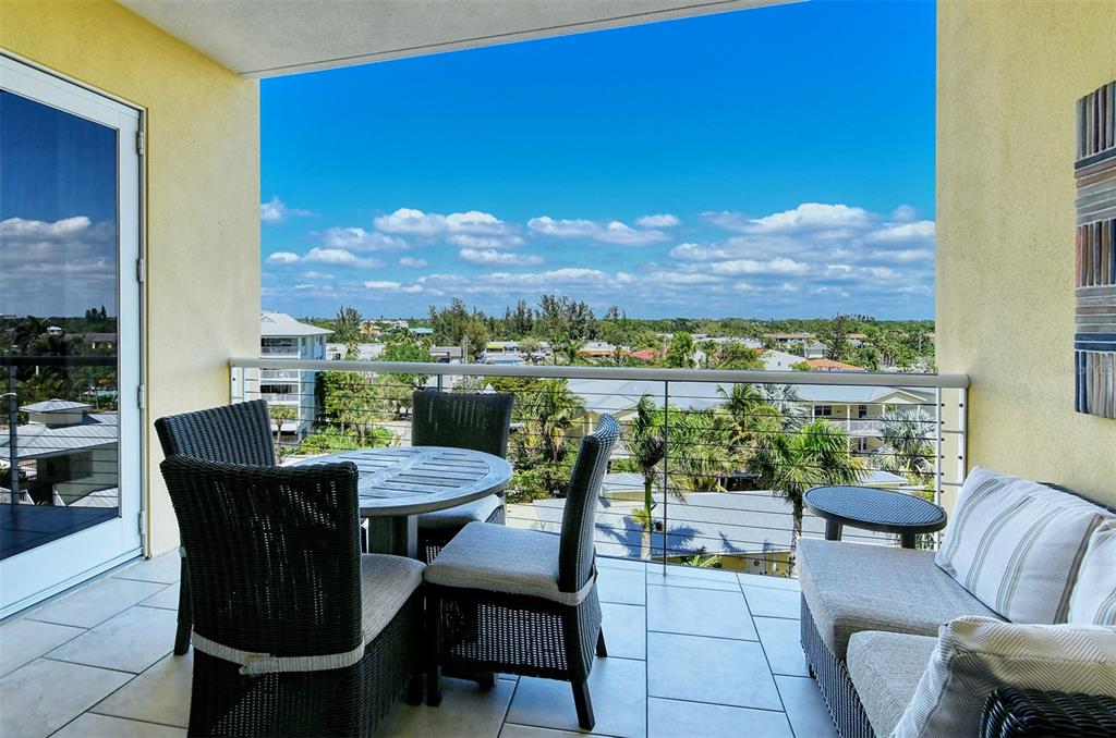 A balcony with wicker furniture, a small table, and a view of surrounding buildings — 915 SEASIDE DRIVE UNIT 607, Weeks 14-15, SARASOTA, FL