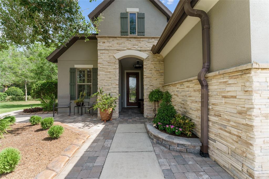 The exterior of a house features a stone facade, a paved walkway, and a front entrance — 9158 SW 65TH LOOP, OCALA, FL