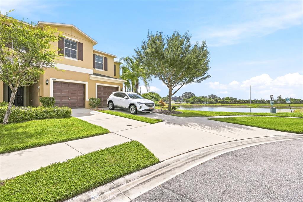A two-story house with a white SUV parked in the driveway near a pond — 12942 UTOPIA GARDENS WAY, RIVERVIEW, FL