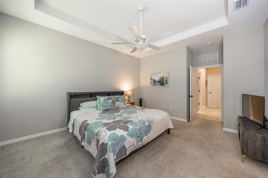 A bedroom features a tray ceiling, a ceiling fan, gray carpeting, and a floral bedspread — 153 PARK PLACE CIRCLE, PALM COAST, FL