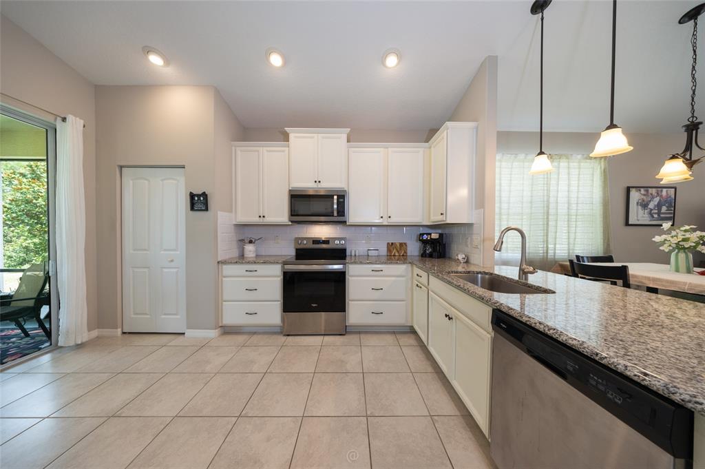 A kitchen features white cabinets, granite countertops, stainless steel appliances, and tile flooring — 153 PARK PLACE CIRCLE, PALM COAST, FL