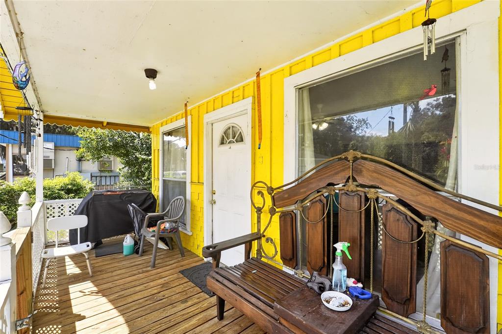 A wooden porch with yellow siding, a white door, and a decorative wooden bench — 7020 SE 221ST STREET, HAWTHORNE, FL