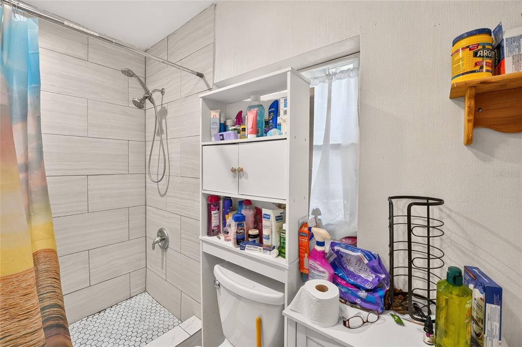 A galley kitchen features white cabinets, wood countertops, light wood flooring, and a ceiling fan — 7020 SE 221ST STREET, HAWTHORNE, FL