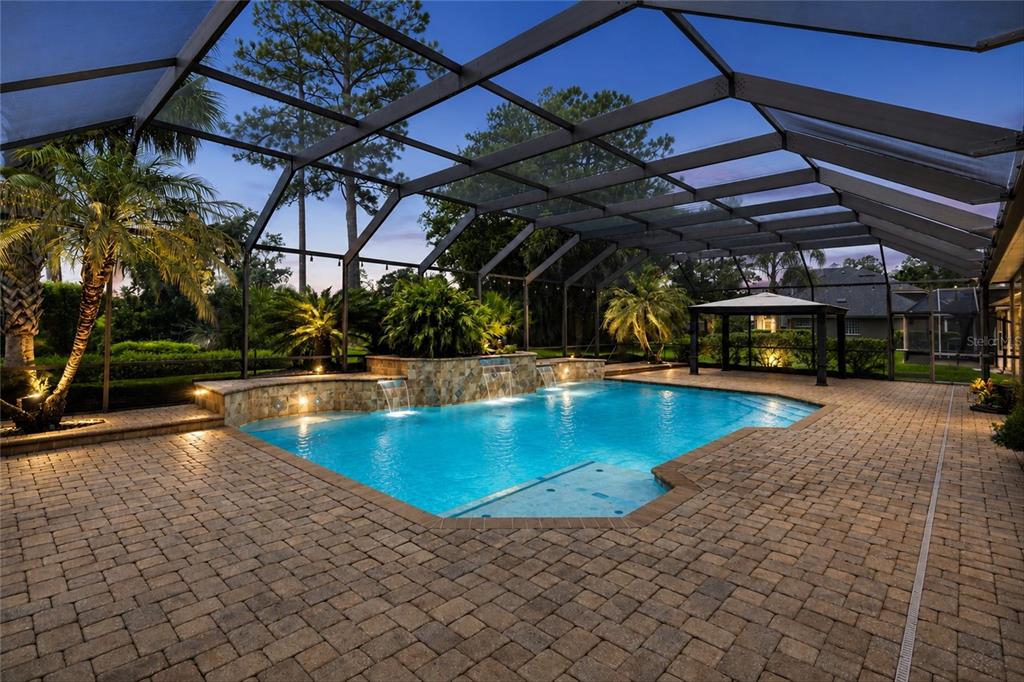 A screened-in patio features a swimming pool with stone water features and paver decking — 1413 COURSE VIEW, FLEMING ISLAND, FL