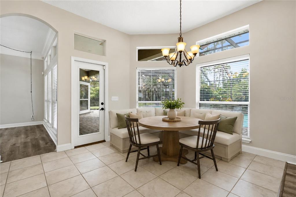 A breakfast nook features a corner banquette, a round wooden table, and a chandelier — 1413 COURSE VIEW, FLEMING ISLAND, FL