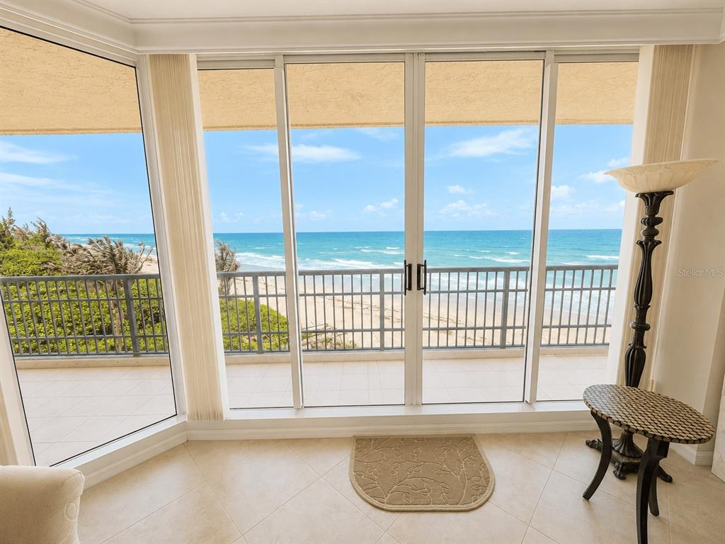 A room with tile floors features large glass doors opening onto a balcony overlooking the ocean — 8600 S OCEAN DRIVE UNIT 402, JENSEN BEACH, FL