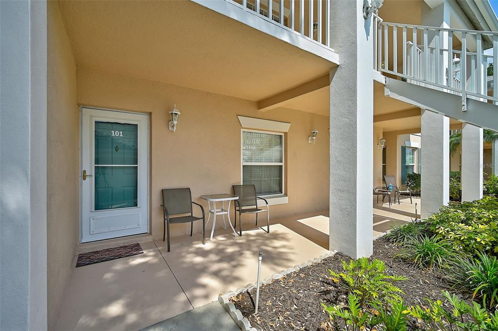 A ground-level patio with two chairs, a small table, and a door marked 101 — 4215 CADDIE DRIVE E UNIT 101, BRADENTON, FL