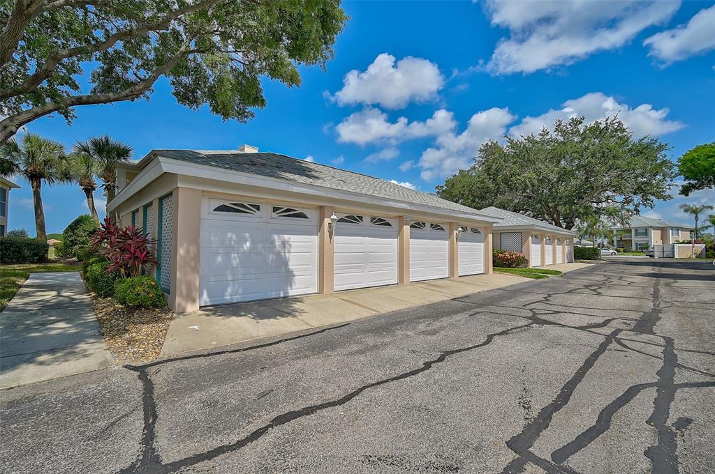 A row of white garage doors on a tan building exterior under a blue sky — 4215 CADDIE DRIVE E UNIT 101, BRADENTON, FL