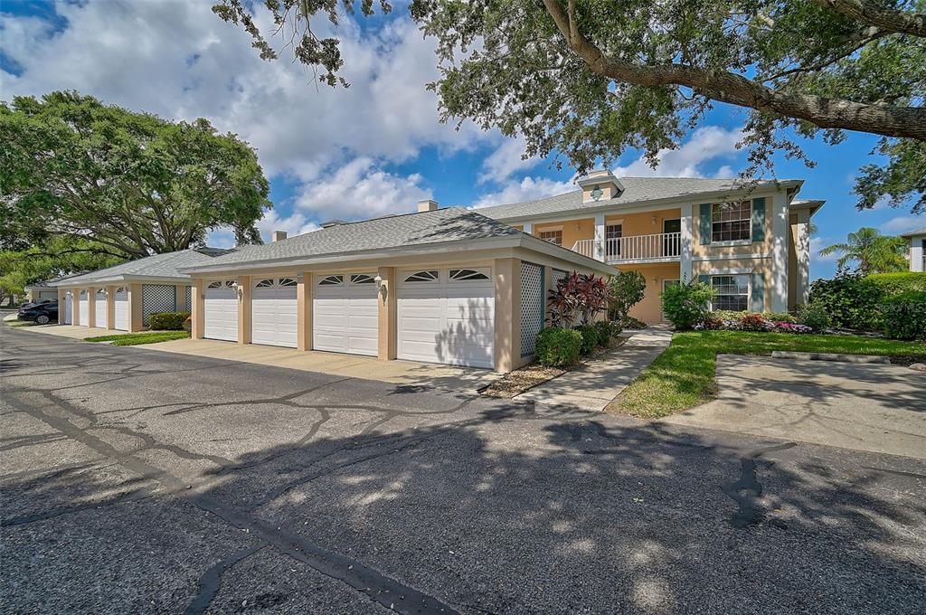 A multi-unit residential building with a row of white garage doors and a second-story balcony — 4215 CADDIE DRIVE E UNIT 101, BRADENTON, FL