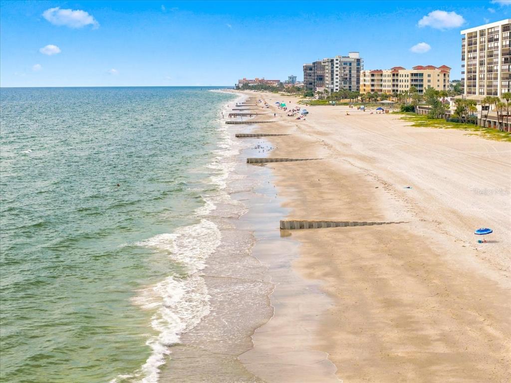 An aerial view of a sandy beach with wooden groynes extending into the ocean — 14800 GULF BOULEVARD UNIT 207, MADEIRA BEACH, FL