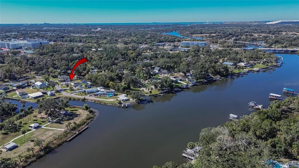 An aerial view shows a waterfront neighborhood with a red arrow pointing to a house — 8615 PARKWAY CIRCLE, RIVERVIEW, FL