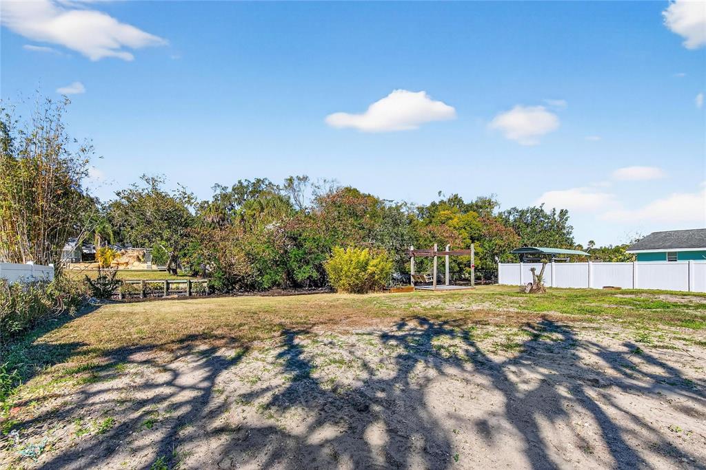 A large, grassy backyard features a wooden pergola, a white fence, and mature trees — 8615 PARKWAY CIRCLE, RIVERVIEW, FL