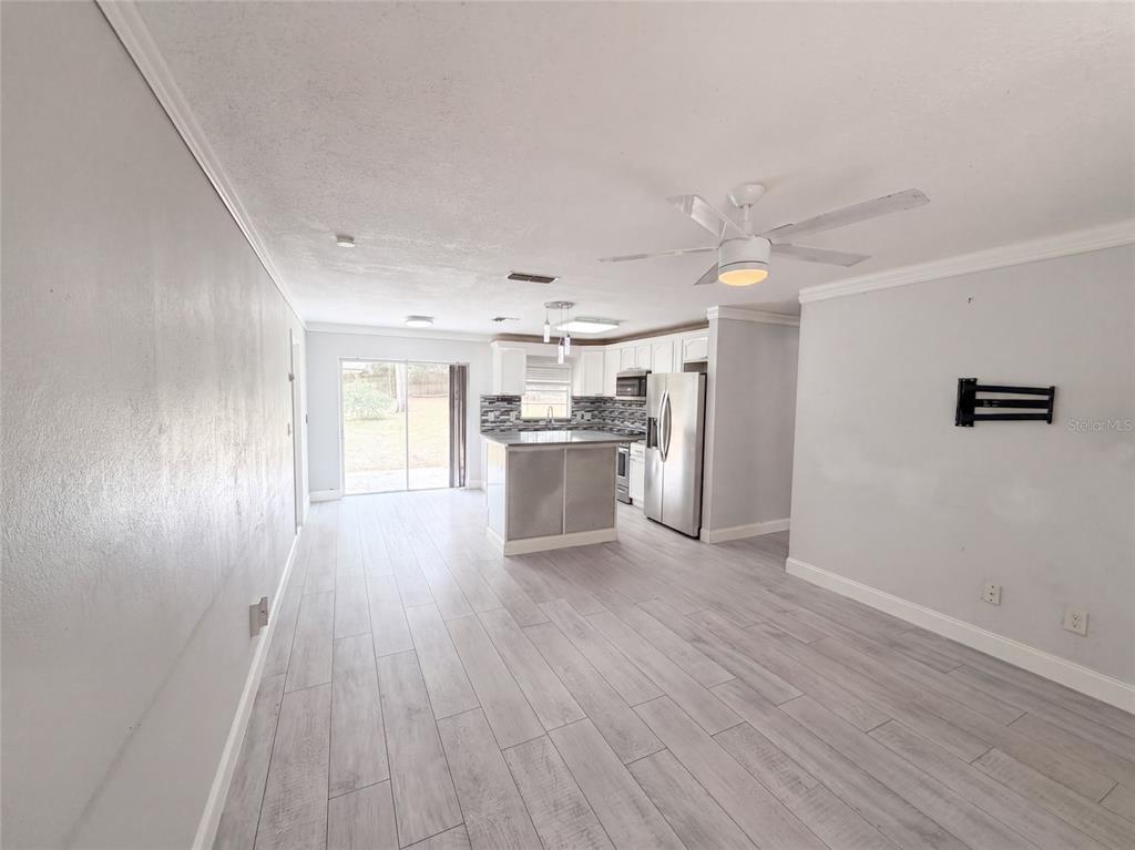 A kitchen with a central island and stainless steel appliances opens into a living area — 976 LISKEARD AVENUE, ORANGE CITY, FL