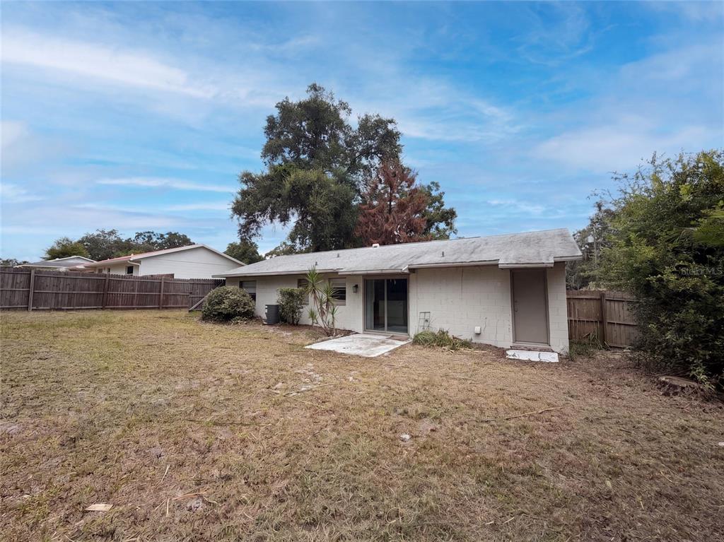 The exterior of a single-story concrete block house features a sliding glass door and backyard — 976 LISKEARD AVENUE, ORANGE CITY, FL