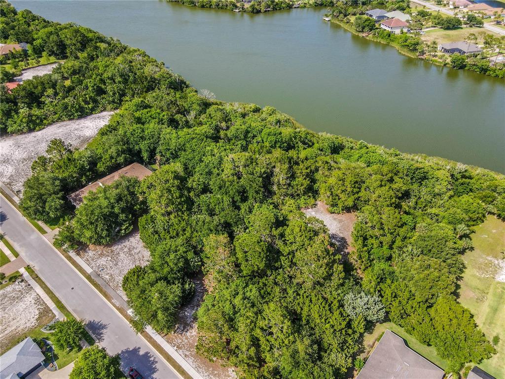 An aerial view shows a wooded residential lot situated along a riverbank — 22 N LAKEWALK DRIVE, PALM COAST, FL