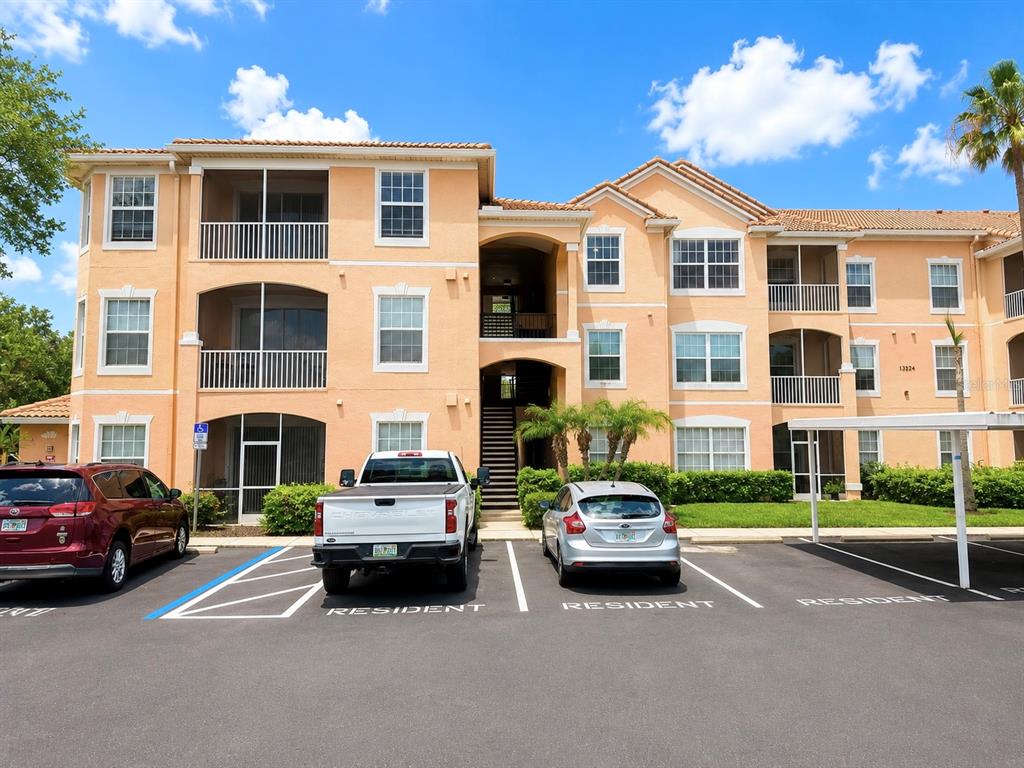A three-story apartment building with a parking lot in front and three parked cars — 13524 TURTLE MARSH LOOP UNIT 634, ORLANDO, FL