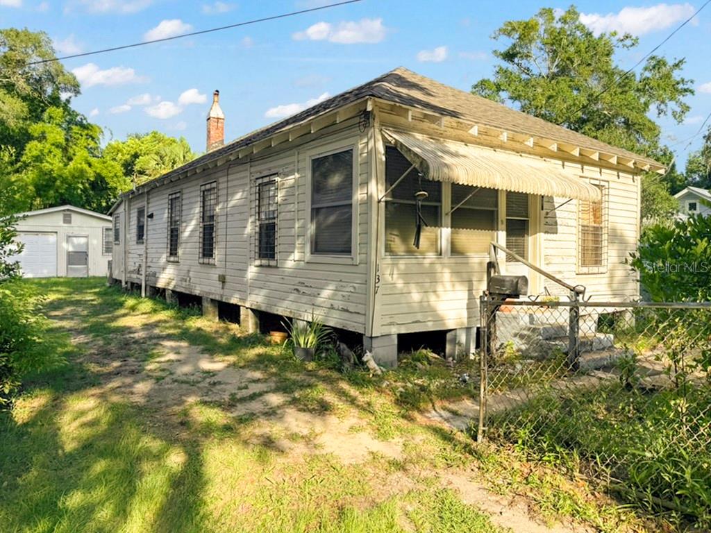 A weathered, single-story white house with a metal awning and a detached garage in back — 137 BLANCO STREET, ST AUGUSTINE, FL