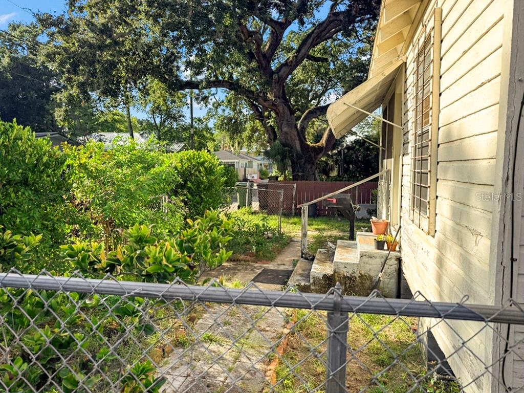 A side view of a house with white siding, a metal awning, and a chain-link fence — 137 BLANCO STREET, ST AUGUSTINE, FL