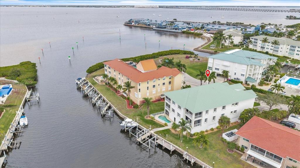 An aerial view shows waterfront condominiums with boat docks and a swimming pool — 129 BREAKERS COURT UNIT 121, PUNTA GORDA, FL
