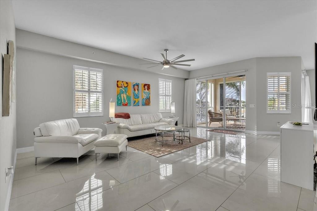 A bright living room features white tile floors, a white sofa set, and sliding glass doors — 129 BREAKERS COURT UNIT 121, PUNTA GORDA, FL