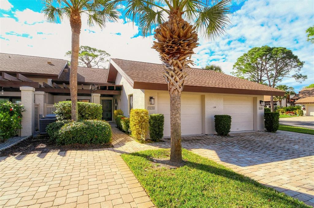A single-story house with a two-car garage, brick paver driveway, and palm trees in front — 3131 WINDRUSH BOURNE UNIT 22, SARASOTA, FL