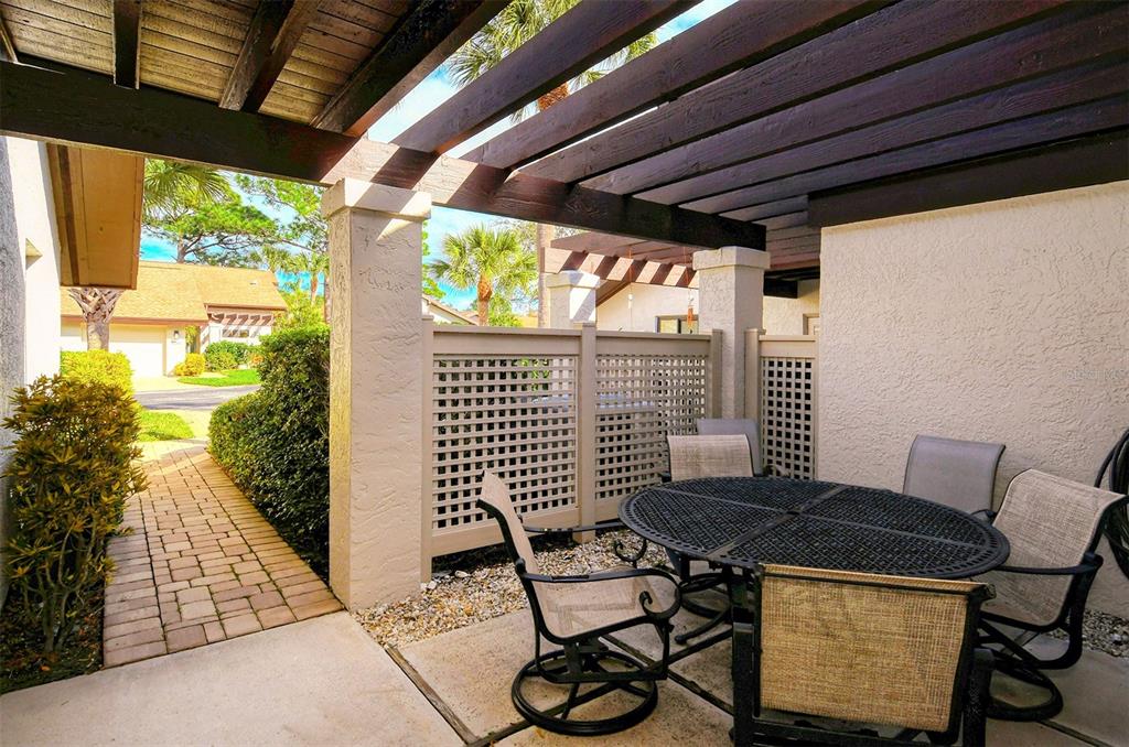 A patio features a pergola, a metal dining set, and a lattice privacy screen — 3131 WINDRUSH BOURNE UNIT 22, SARASOTA, FL