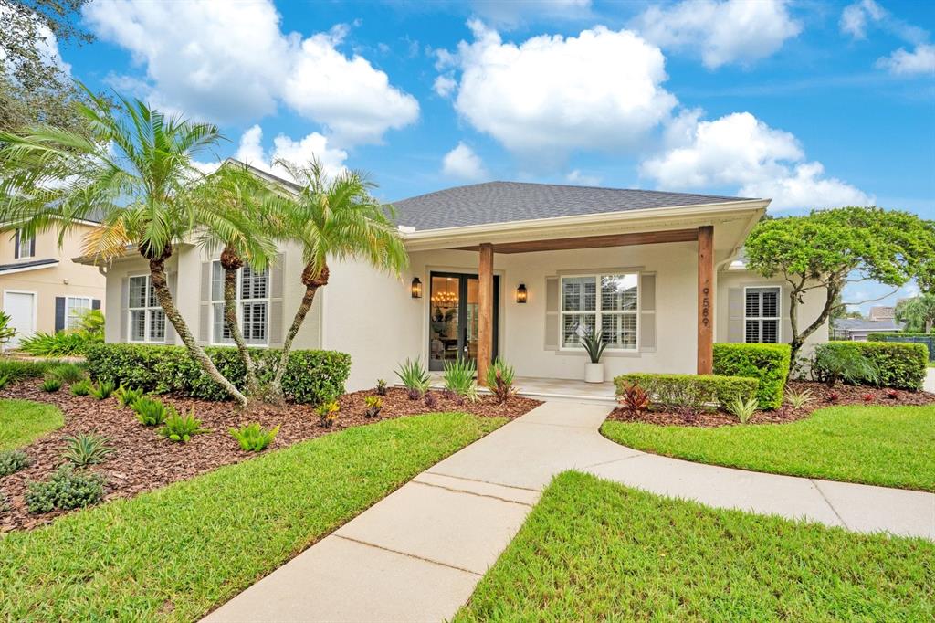 A single-story house with a beige exterior, gray shutters, and a landscaped front yard — 9589 PINE LILY STREET, ORLANDO, FL