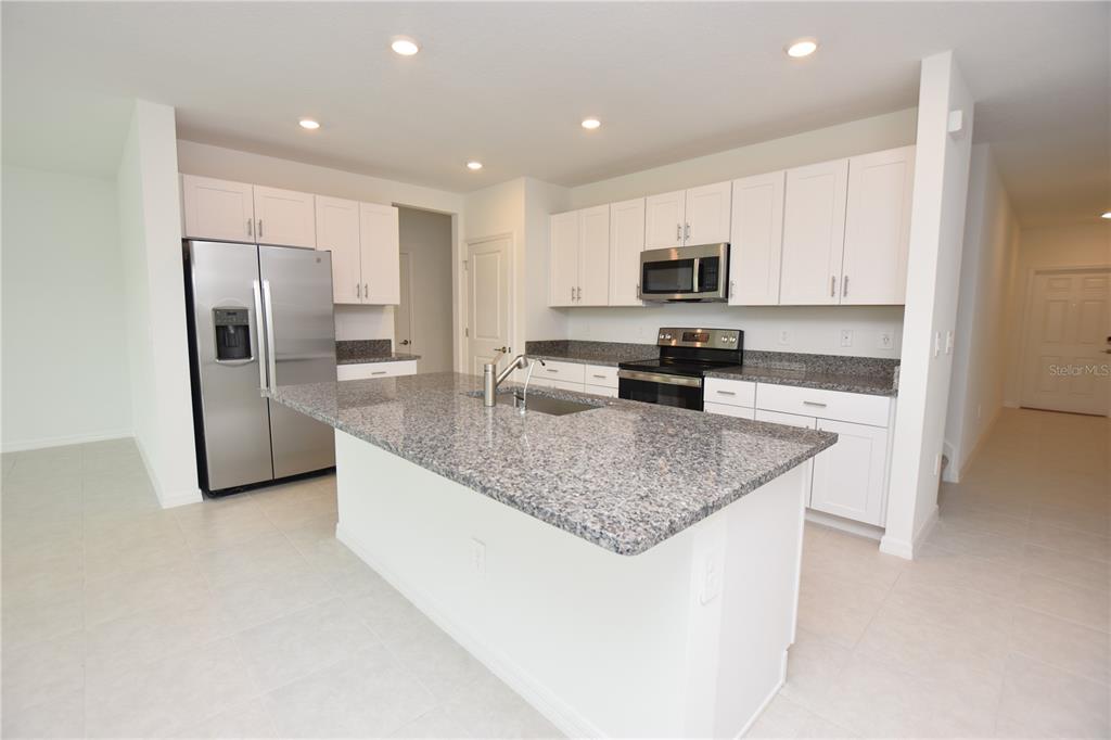 A kitchen features white cabinets, granite countertops, stainless steel appliances, and a central island — 1855 RED LOOP, LAKELAND, FL