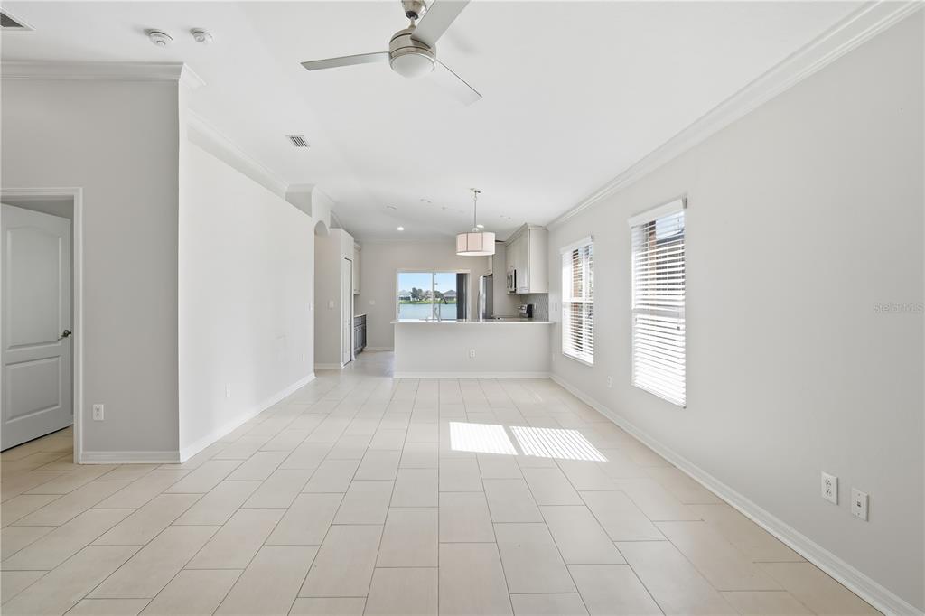 A bright, open-concept living and kitchen area with light tile flooring and a ceiling fan — 31123 MASENA DRIVE, WESLEY CHAPEL, FL