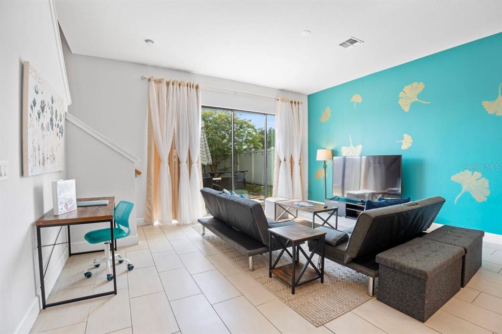 A living room features a bright teal accent wall with gold leaf decals and tile flooring — 184 VILLA DOMANI CIRCLE, DAVENPORT, FL