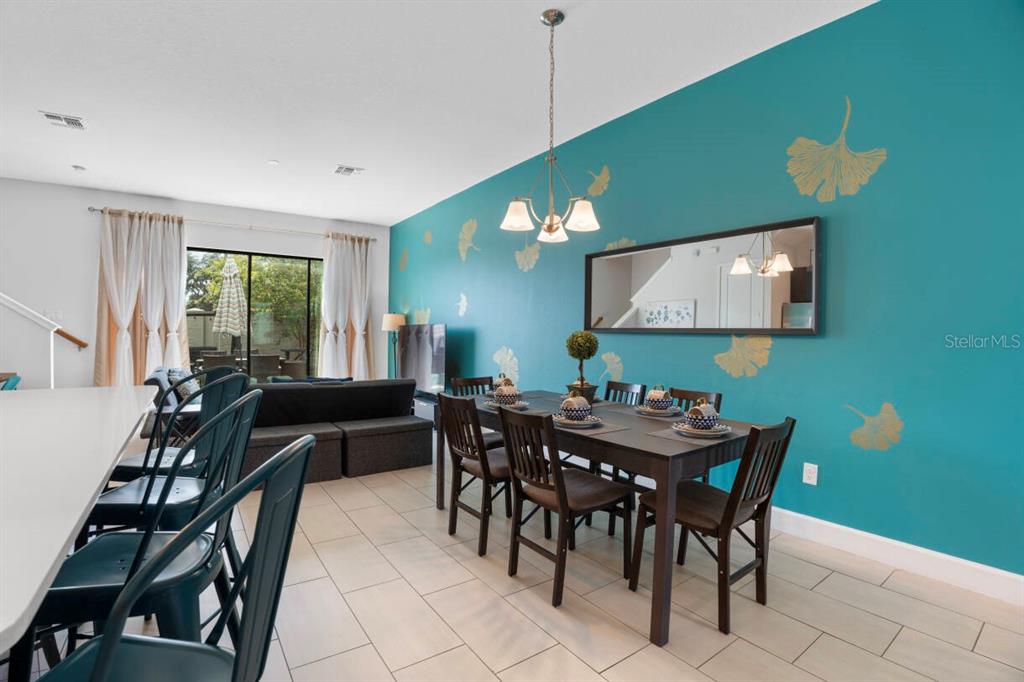 A dining area features a dark wood table, teal accent wall with gold decals, and mirror — 184 VILLA DOMANI CIRCLE, DAVENPORT, FL