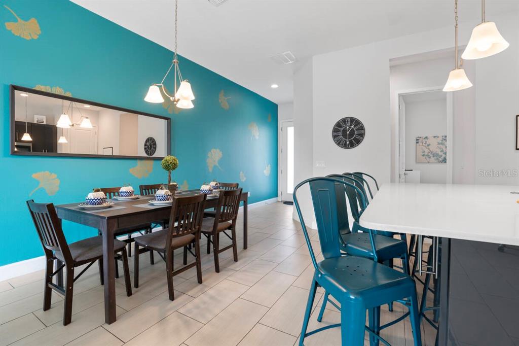 A dining area with a teal accent wall, dark wood table, and metal bar stools — 184 VILLA DOMANI CIRCLE, DAVENPORT, FL
