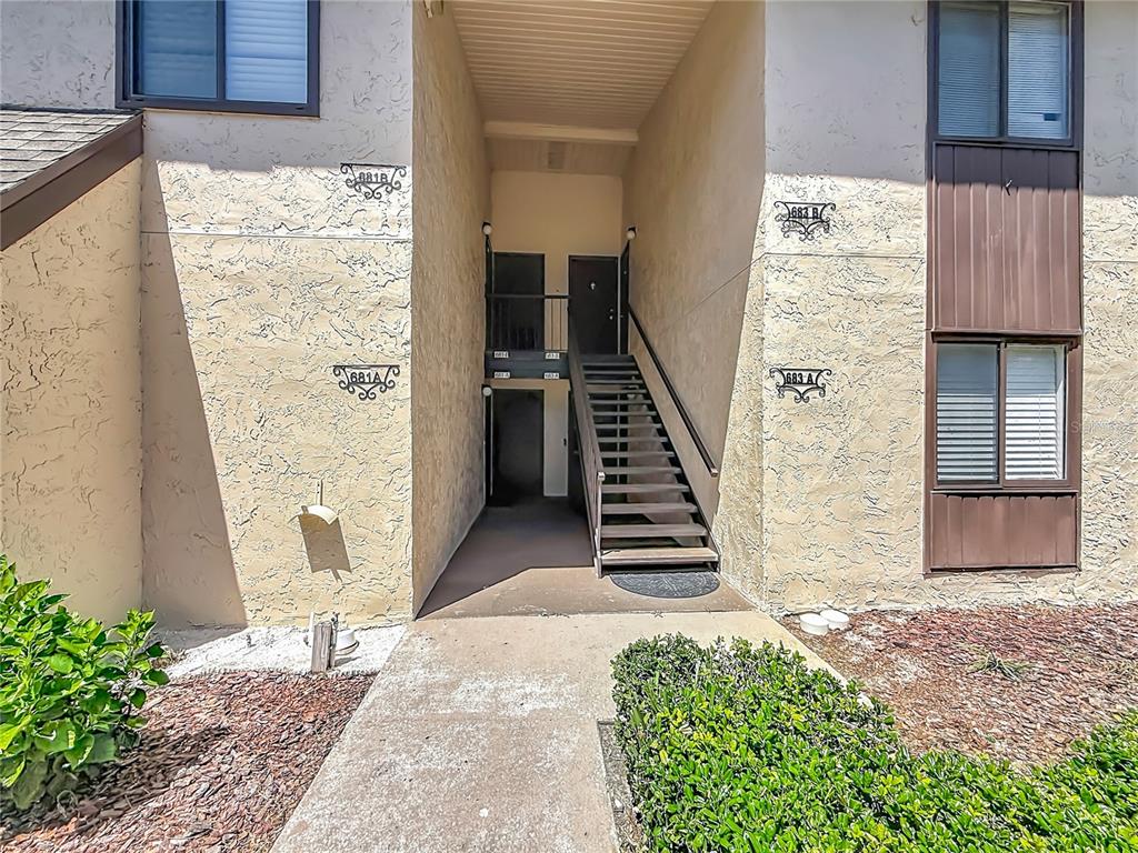 An exterior view of a two-story apartment building with a central staircase and walkways — 681 MIDWAY DRIVE UNIT A, OCALA, FL