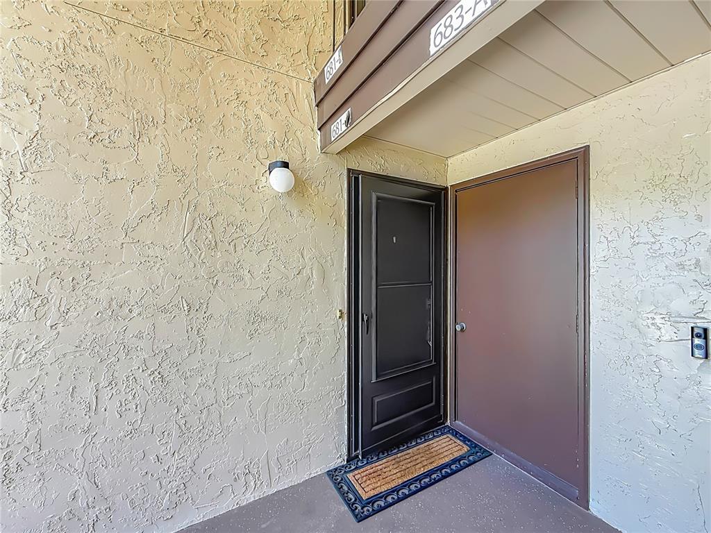 A brown door and a black storm door are set against a textured beige wall — 681 MIDWAY DRIVE UNIT A, OCALA, FL