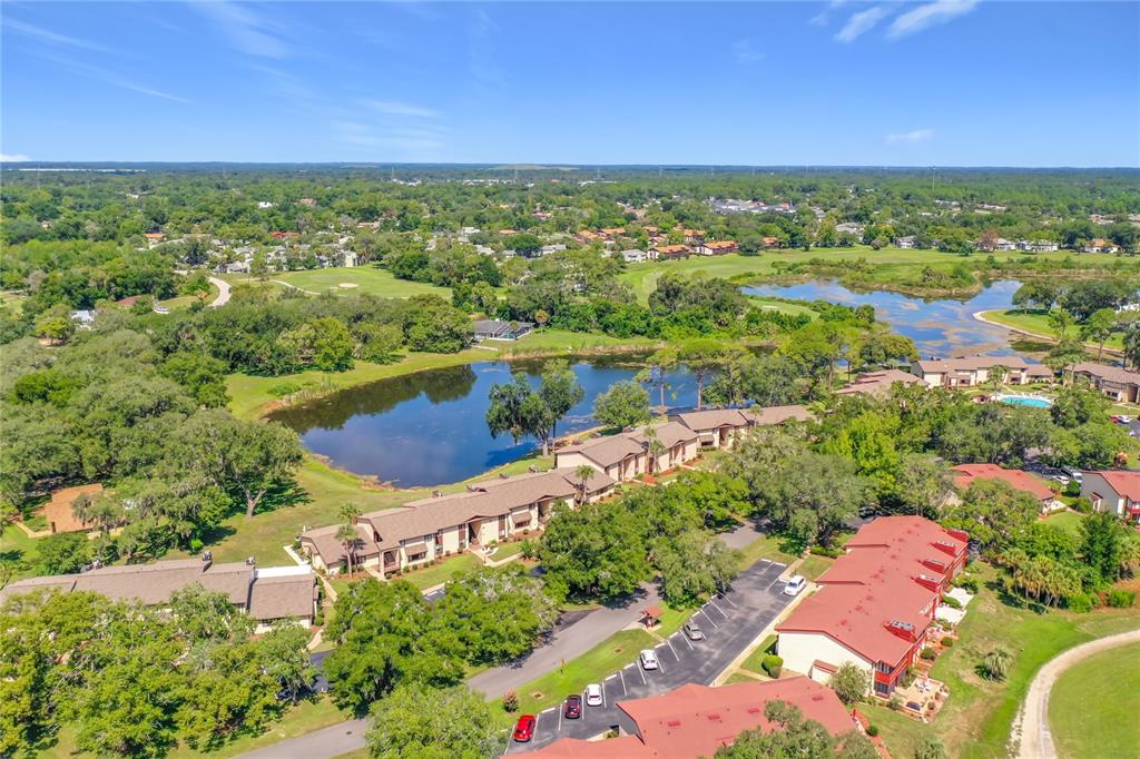 An aerial view shows multi-story residential buildings situated near a pond and a golf course — 681 MIDWAY DRIVE UNIT A, OCALA, FL