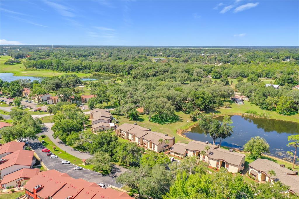 An aerial view shows multi-family residential buildings surrounded by trees and a small lake — 681 MIDWAY DRIVE UNIT A, OCALA, FL