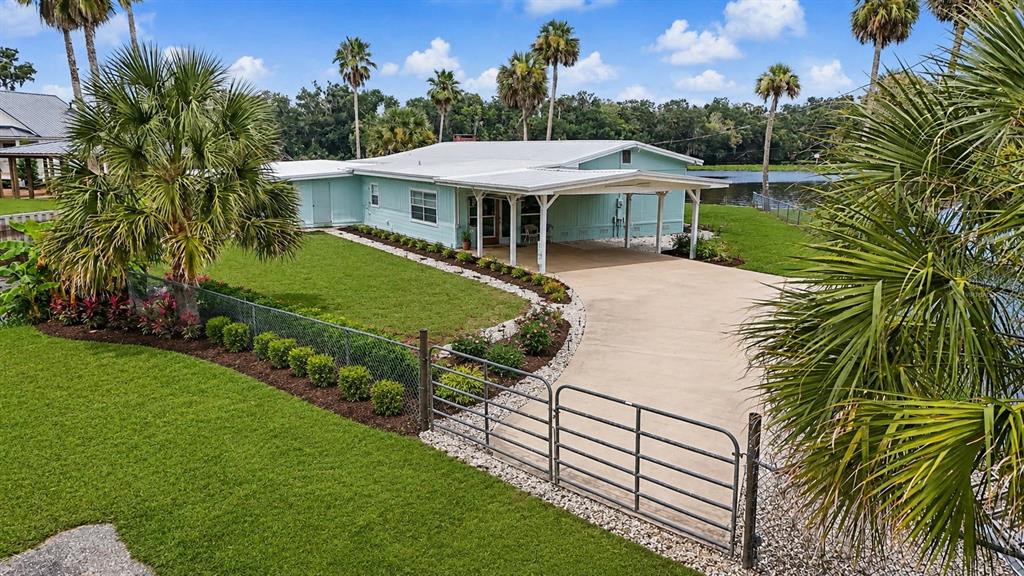 A light blue house with a metal roof and a concrete driveway sits near water — 56440 WATER OAK ROAD, ASTOR, FL