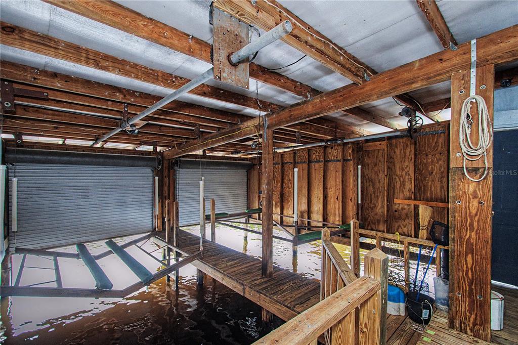 A covered boat slip with wooden framing, a metal roof, and two roll-up garage doors — 56440 WATER OAK ROAD, ASTOR, FL