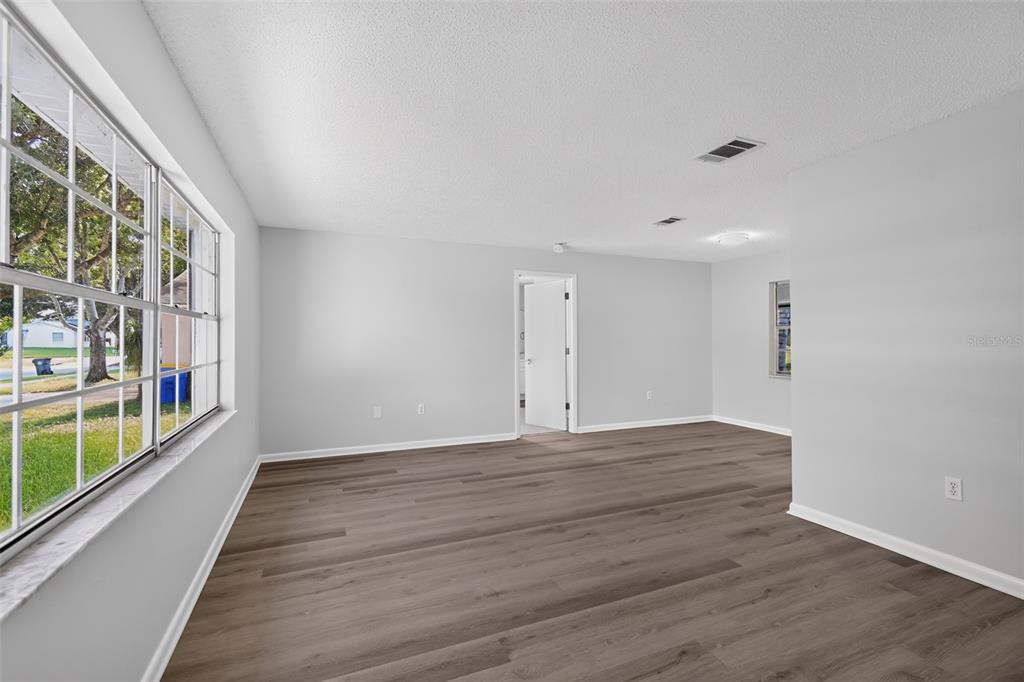 An empty room with light gray walls, wood-look flooring, and a large window — 837 WESTPORT DRIVE, ROCKLEDGE, FL
