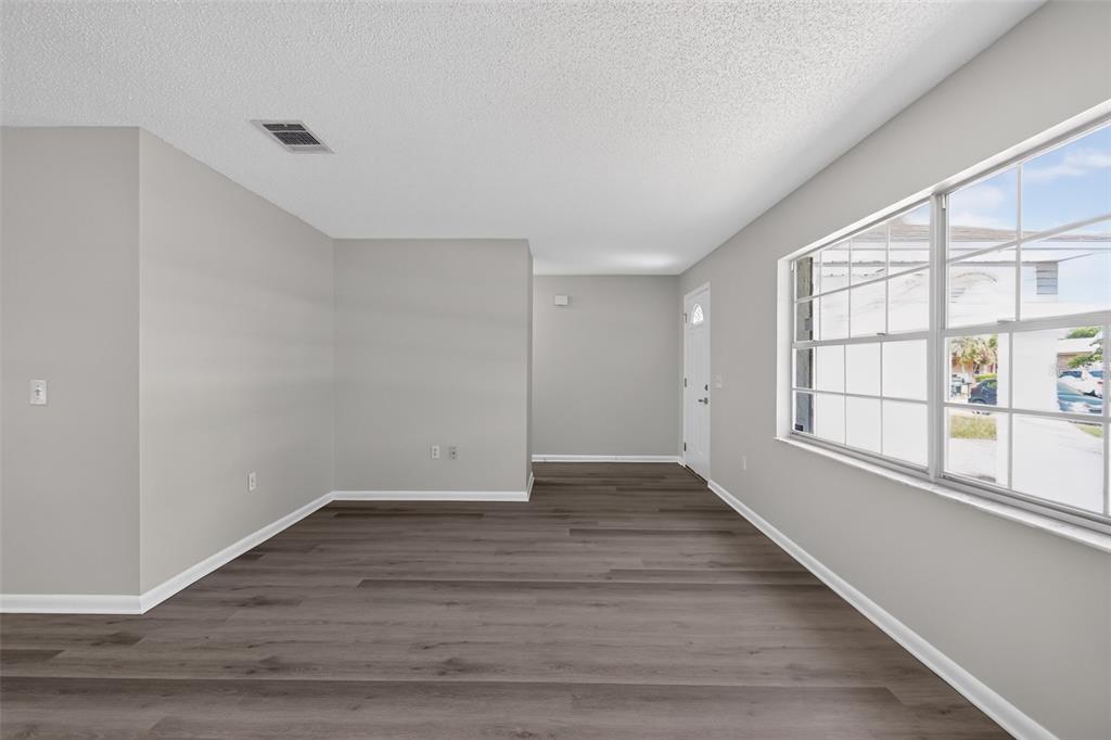 An empty room with gray walls, dark wood-look flooring, and a large window — 837 WESTPORT DRIVE, ROCKLEDGE, FL