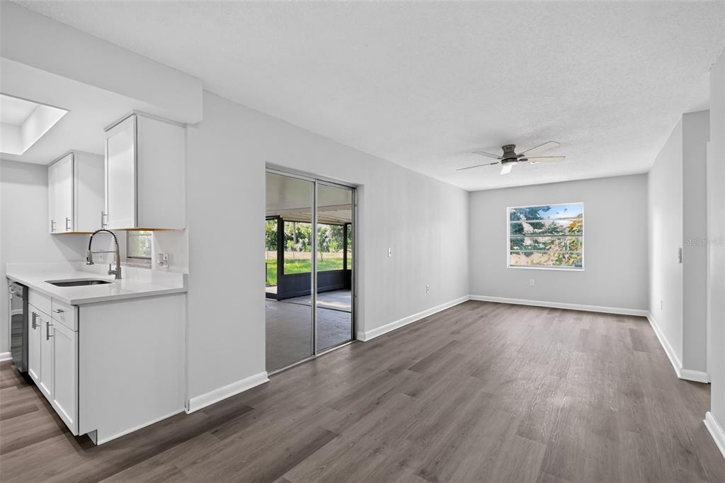 A kitchen with white cabinets and a dining area featuring wood-look floors and sliding doors — 837 WESTPORT DRIVE, ROCKLEDGE, FL