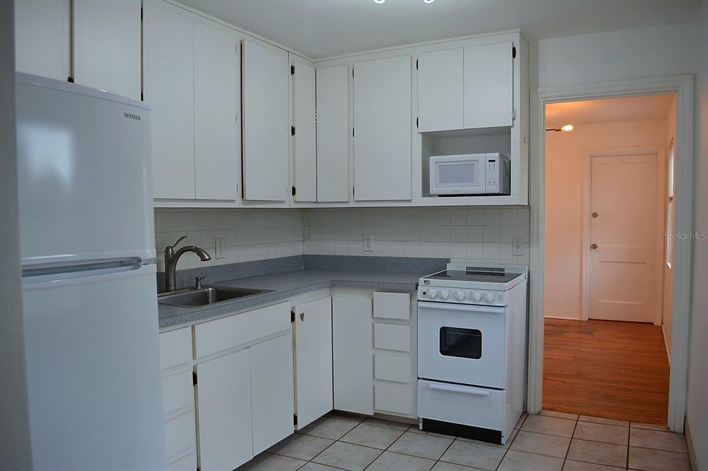 A white kitchen features white cabinets, a gray countertop, a white stove, and a microwave — 1401 34TH AVENUE N, ST PETERSBURG, FL