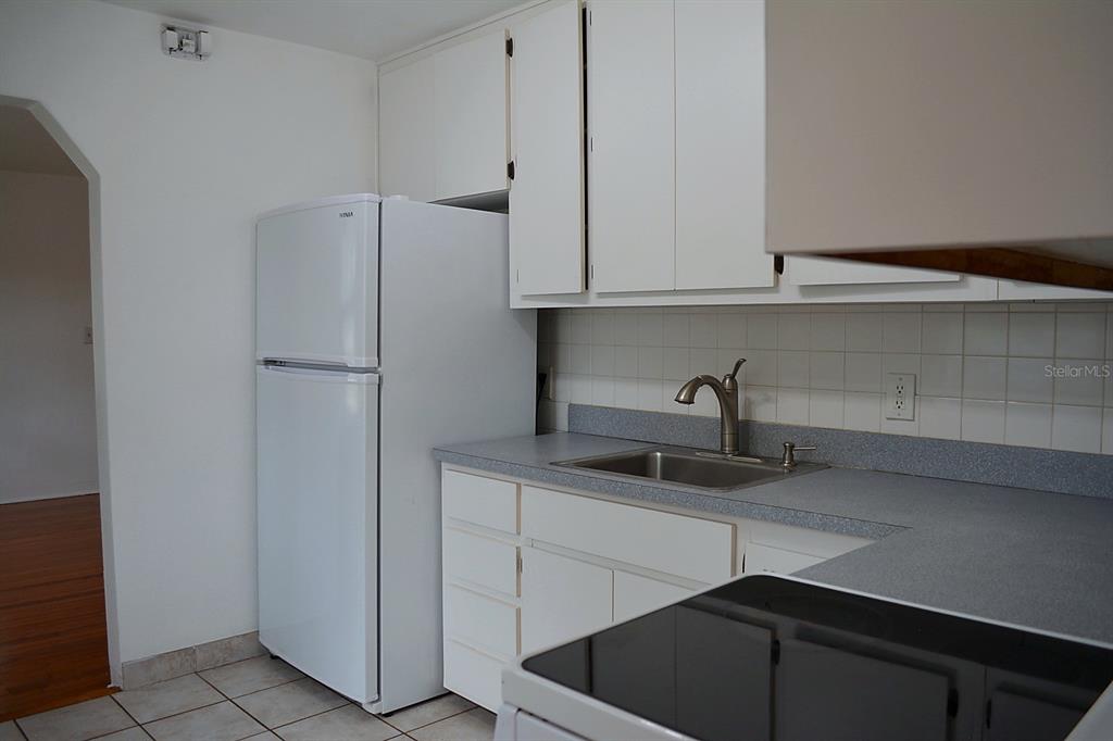 A kitchen features white cabinets, a stainless steel sink, a white refrigerator, and gray countertops — 1401 34TH AVENUE N, ST PETERSBURG, FL