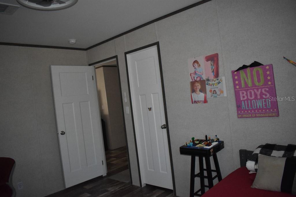 A bedroom features light-colored walls, two white doors, and a sign reading No Boys Allowed — 13230 NE 9TH STREET, WILLISTON, FL
