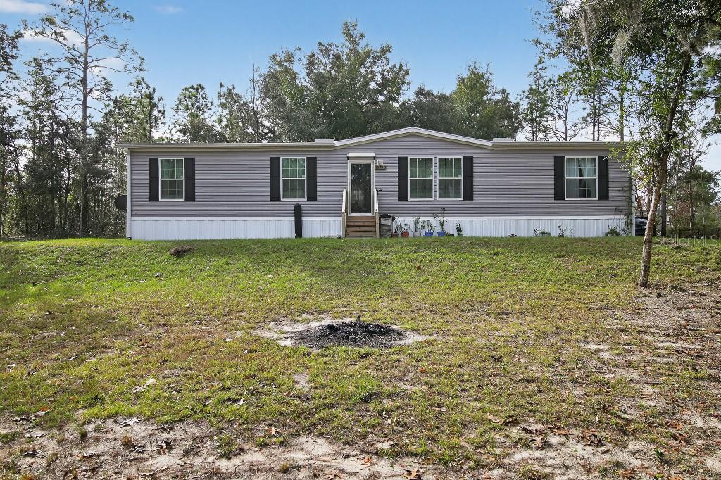 A single-story manufactured home with gray siding sits on a grassy lot — 13230 NE 9TH STREET, WILLISTON, FL