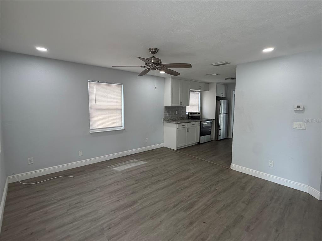 A living room with gray wood-look flooring leads into a kitchen with white cabinetry — 4735 21ST AVENUE N, ST PETERSBURG, FL